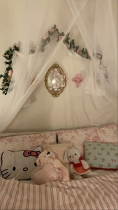 two stuffed animals sitting on top of a bed in a room with white walls and curtains