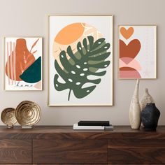 three framed art prints on a wall above a dresser