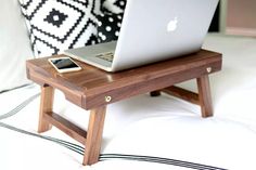 a laptop computer sitting on top of a wooden table next to a cell phone and charger