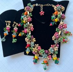 Here is a rare and absolutely stunning vintage necklace and earrings set by Miriam Haskell. This jewelry is artfully fashioned in a decadent fruit design that is composed of dangling clusters of multi colored wooden beads, gleaming gilt filigree capped acorn beads, glistening and translucent glass bell flowers and green glass leaves. The beautiful colors of the beads include pinks, greens, blues, yellows and orange. The choker style necklace is fashioned as a single strand, lushly beaded with an Miriam Haskell Necklace, Miriam Haskell Jewelry, Designer Costume Jewelry, Jewelry Styles, Choker Style Necklace, Translucent Glass, Miriam Haskell, Fruit Design, Fashion Jewelry Sets