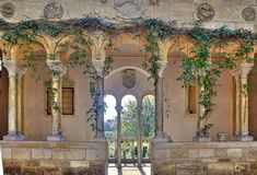 an archway with vines growing on the side of it and stone pillars in front of it