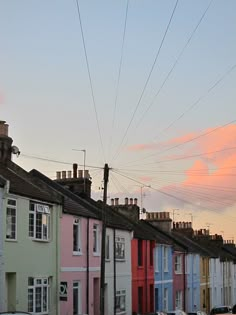 a row of houses with power lines above them and cars parked on the street below