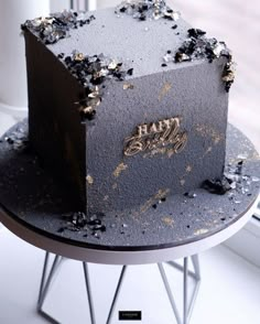 a black cake with gold sprinkles on it