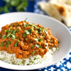 a white bowl filled with rice covered in sauce and garnished with cilantro