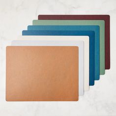 five different colored folders sitting on top of a white countertop next to each other