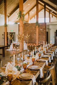 a long table set with place settings and candles for an event or wedding reception in a large room