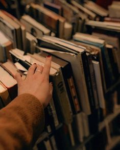 a person reaching for books on a shelf