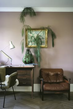 a living room with a chair, desk and potted plant on the wall next to it