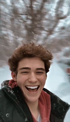 a young man smiling while standing in the snow