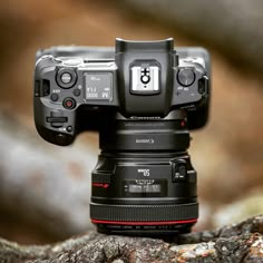 a canon camera sitting on top of a rock with the lens attached to it's body