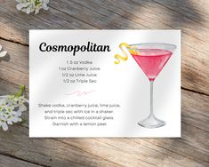 a pink cocktail sitting on top of a wooden table next to white and yellow flowers