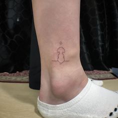 a small tattoo on the ankle of a woman's foot, depicting a dog