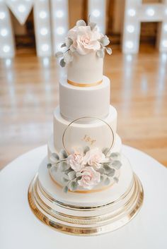 a three tiered wedding cake with pink flowers on the top and gold trimmings