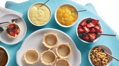 a table topped with white plates filled with desserts and fruit on top of it