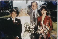 a man and two women standing next to each other in front of a tree with flowers