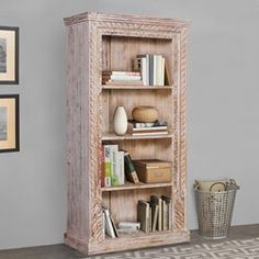 a book shelf with books on top of it next to a basket and framed pictures