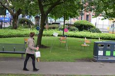 a woman walking down a sidewalk next to a park