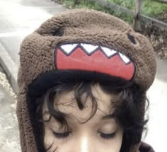 a young child wearing a brown hat with monster teeth