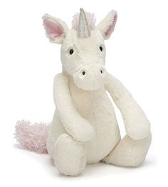 a white stuffed unicorn sitting on the ground