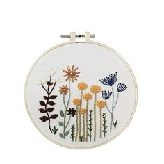 an embroidery kit with flowers and leaves on the front, in white fabric hoop frame