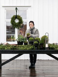 a woman sitting at a table covered in plants