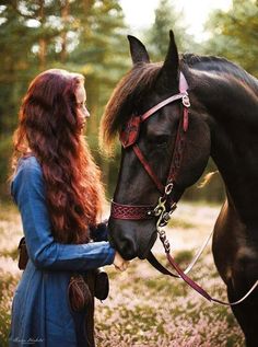 a woman standing next to a brown horse