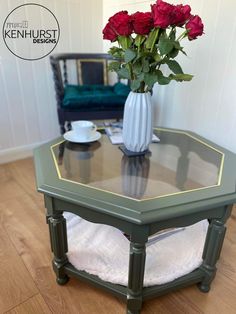 a vase with roses sitting on top of a glass table in front of a couch