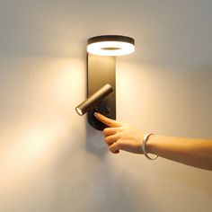 a person's hand is pointing at a light on the wall with a flashlight