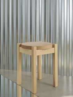 a wooden stool sitting in front of a metal wall