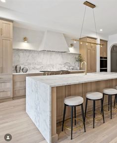 a kitchen with marble counter tops and stools next to an island in the middle