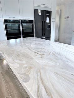 a kitchen with marble counter tops and black ovens in the backround area