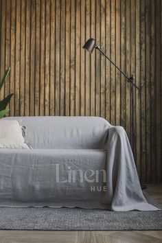 a living room with a couch, lamp and wooden wall behind it that says linen hue