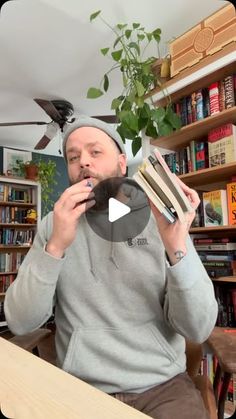 a man sitting at a table with books in front of him and holding a book