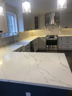 a kitchen with white marble counter tops and stainless steel appliances in the middle of it