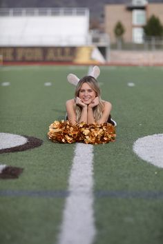 a woman laying on the ground with her legs crossed and wearing cheerleader gear, smiling