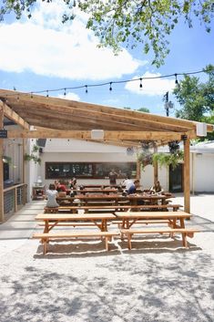 an outdoor seating area with wooden benches and string lights