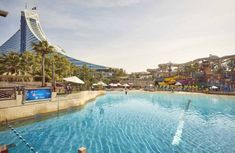 an outdoor swimming pool with water slides and trees in the background at a theme park