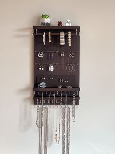 a wall mounted jewelry rack with several pairs of earrings hanging from it's sides