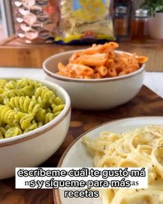 two bowls filled with pasta and vegetables on top of a wooden table next to another bowl