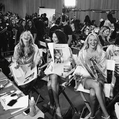 black and white photograph of four women sitting in chairs with magazine covers on their laps