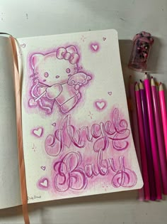 an open notebook with hello kitty on it next to some colored pencils and markers