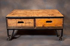 an old wooden table with two drawers on it's legs and wheels, against a gray background