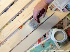 a person is using a knife to cut paper on the floor next to a cup of coffee