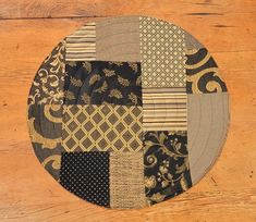 a wooden table topped with a black and gold patchwork plate