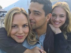 two women and a man are smiling for the camera with their arms around each other