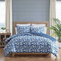 a bed with blue and white flowers on it in a room next to a window