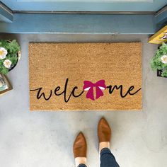 a person standing in front of a welcome mat with a pink bow on the door