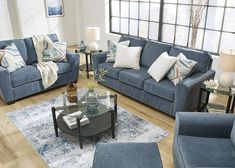 a living room filled with blue couches and pillows on top of a wooden floor