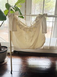 a white hammock hanging from the side of a window next to a potted plant