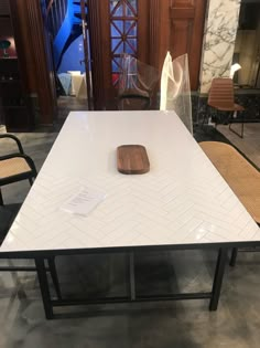 a white table with a wooden tabletop on it in the middle of a room